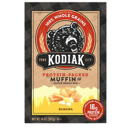 A package of Kodiak City Protein-Packed Muffin and Quick Bread Mix in Banana flavor. The box features a brown kraft-paper style center with a black bear logo inside a red circle, and an illustration of banana muffins at the bottom.